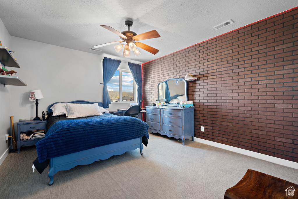 Bedroom featuring visible vents, a textured ceiling, brick wall, and light carpet