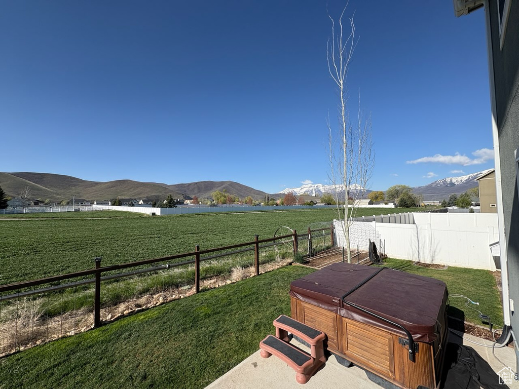 View of yard with fence, a mountain view, a hot tub, and a rural view