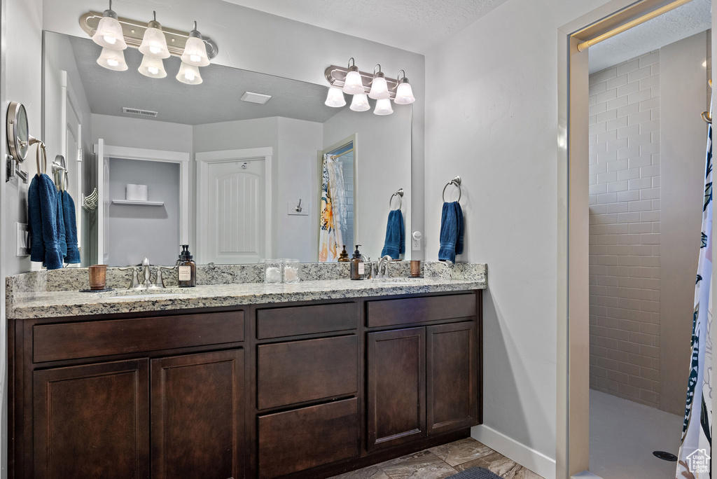 Full bath with a sink, a tile shower, double vanity, and visible vents