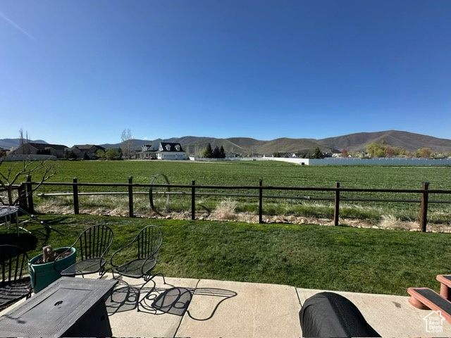 View of patio with a mountain view, fence, and a rural view