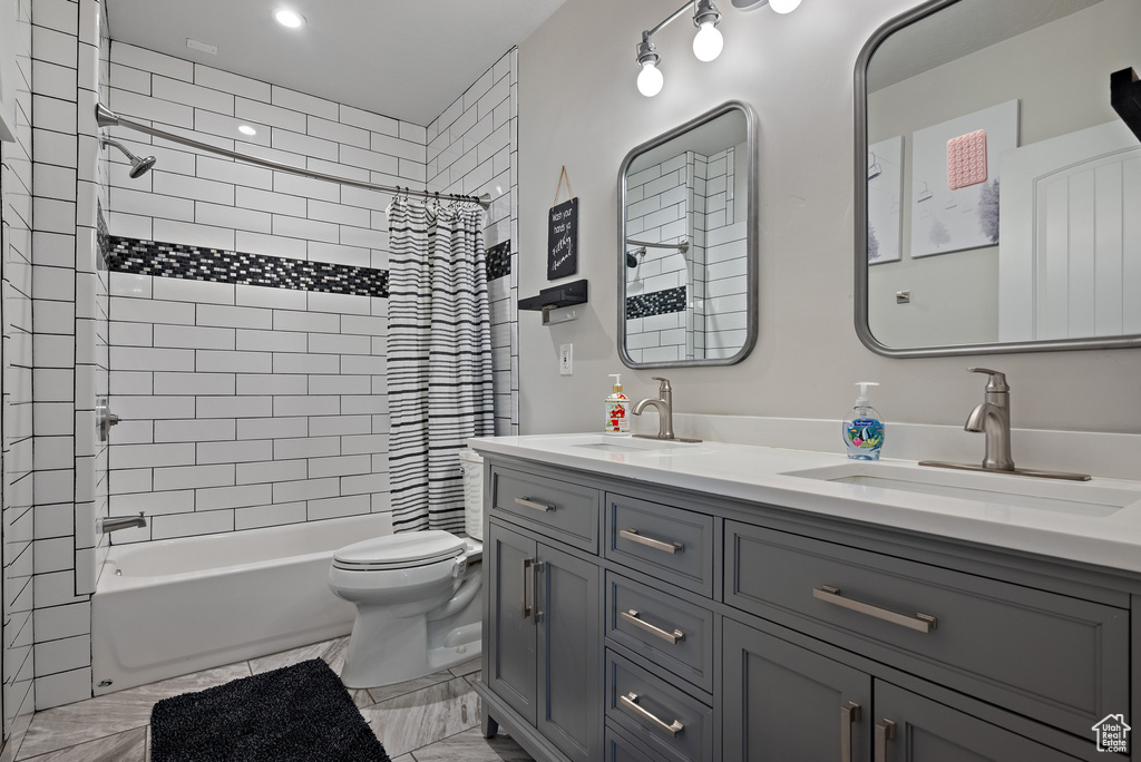 Bathroom featuring double vanity, a sink, shower / bath combo, and toilet