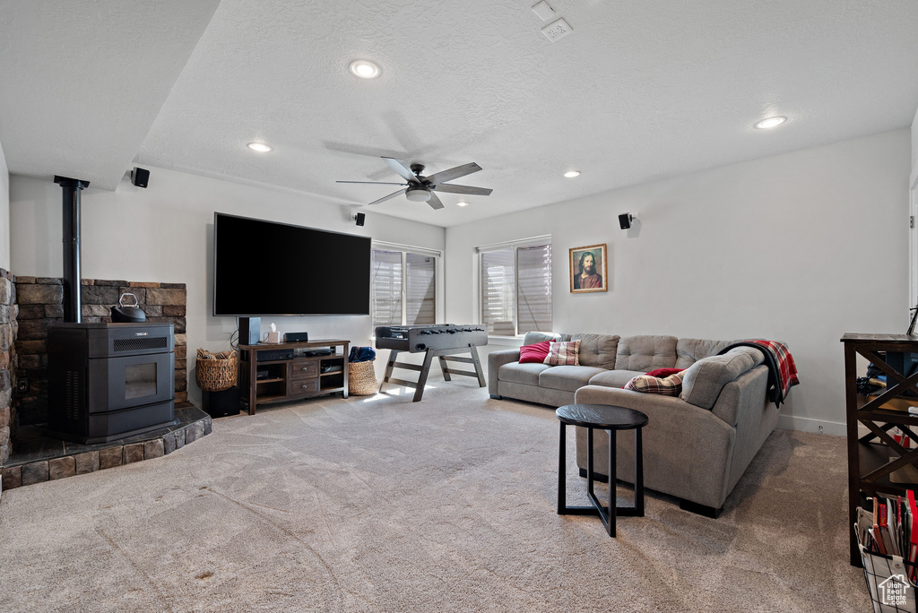 Living room with ceiling fan, carpet, a wood stove, and recessed lighting