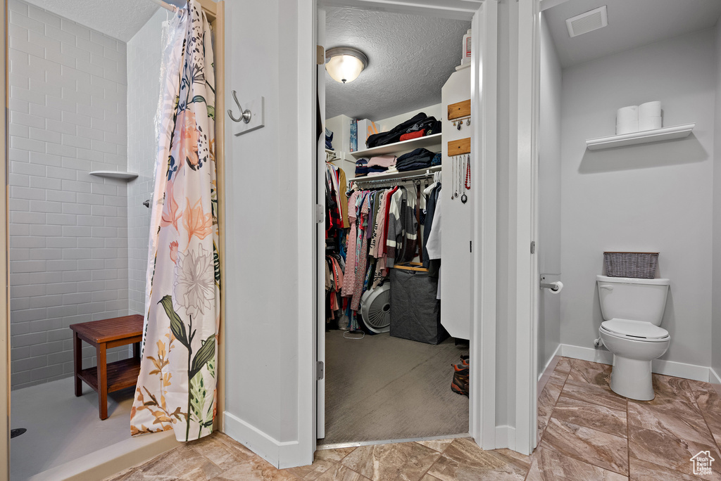 Bathroom featuring visible vents, toilet, baseboards, a spacious closet, and a shower stall