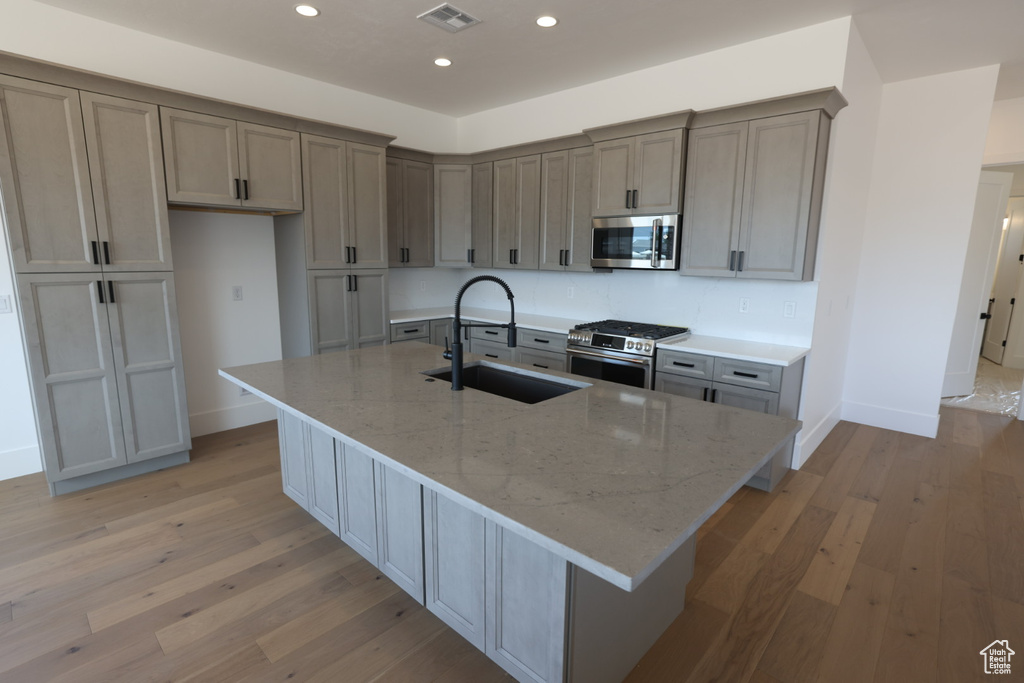 Kitchen with appliances with stainless steel finishes, a sink, visible vents, and light wood-type flooring