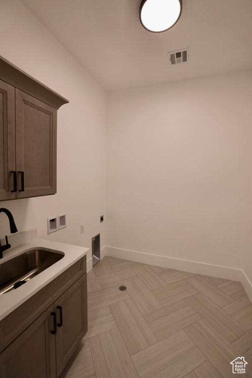 Clothes washing area featuring visible vents, baseboards, hookup for a washing machine, electric dryer hookup, and a sink