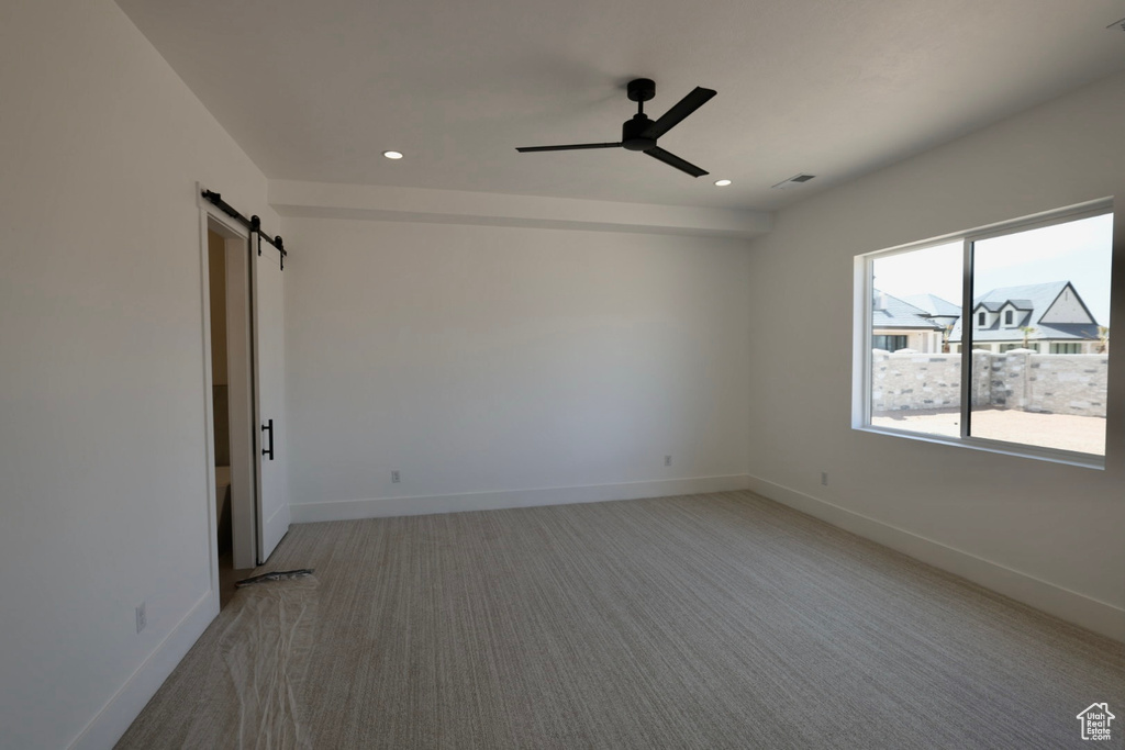 Spare room with recessed lighting, a barn door, a ceiling fan, and light carpet