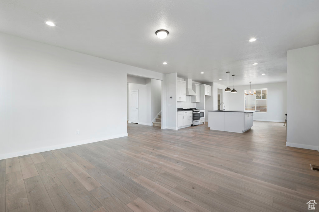 Unfurnished living room with visible vents, a sink, baseboards, light wood finished floors, and recessed lighting