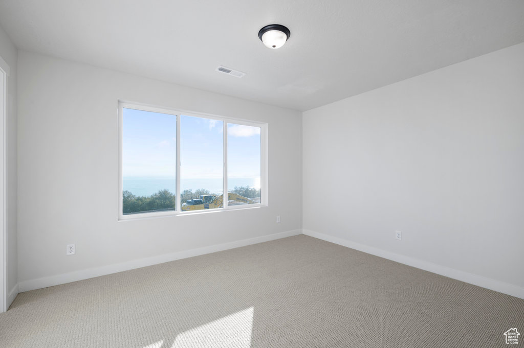 Carpeted spare room featuring baseboards and visible vents