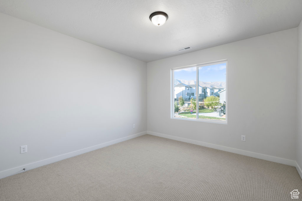 Empty room with baseboards, light carpet, and visible vents
