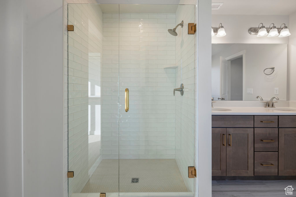 Bathroom featuring double vanity, a stall shower, and a sink