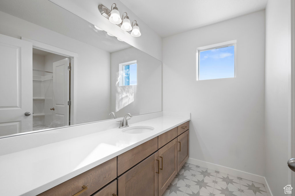 Bathroom featuring baseboards, vanity, tile patterned floors, and a wealth of natural light
