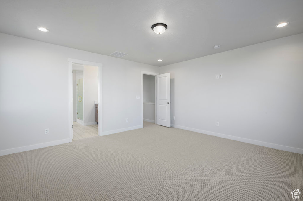 Unfurnished bedroom with visible vents, light colored carpet, baseboards, ensuite bathroom, and recessed lighting