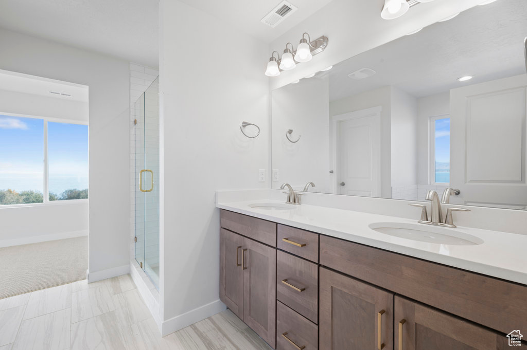 Full bathroom featuring visible vents, a sink, double vanity, and a shower stall