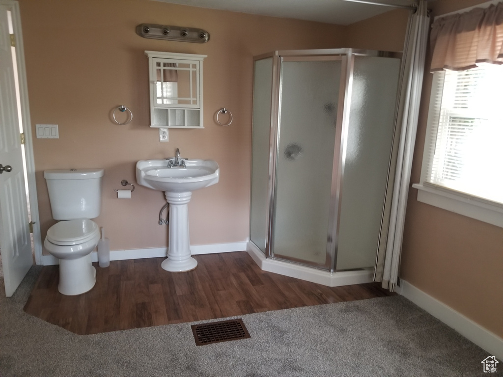 Full bathroom featuring toilet, baseboards, wood finished floors, visible vents, and a stall shower