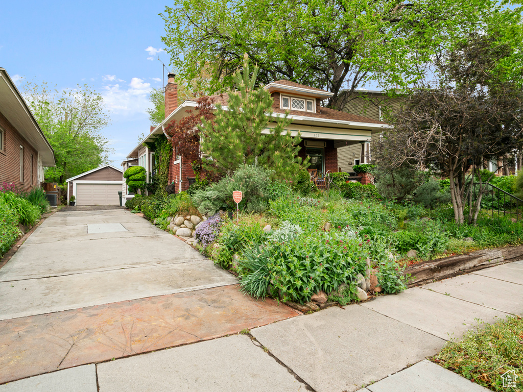 Bungalow-style house featuring brick siding, an outbuilding, a chimney, and a detached garage