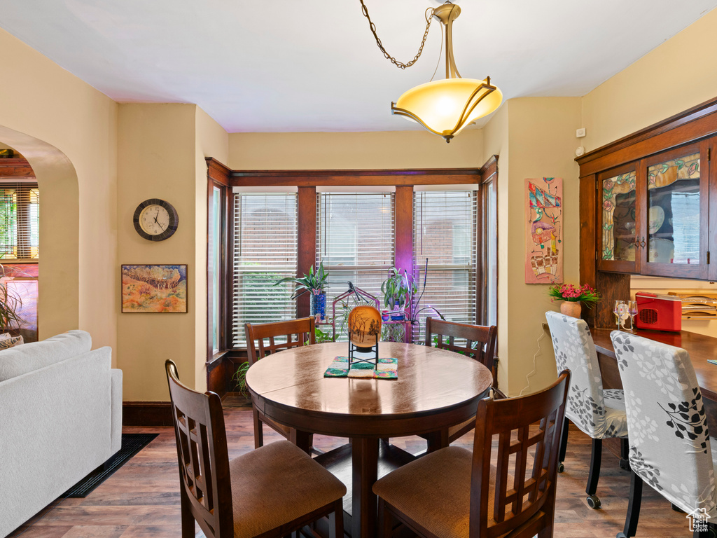 Dining area with arched walkways and wood finished floors