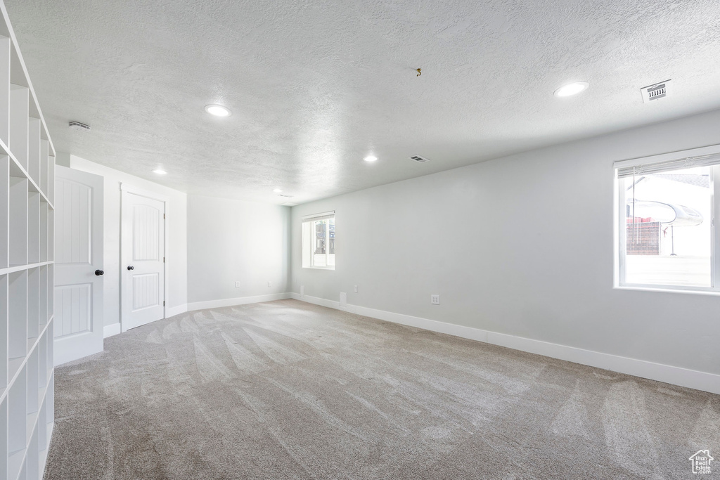 Spare room with a textured ceiling, visible vents, baseboards, light carpet, and recessed lighting