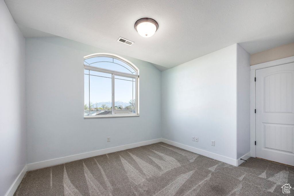 Carpeted empty room featuring baseboards and visible vents