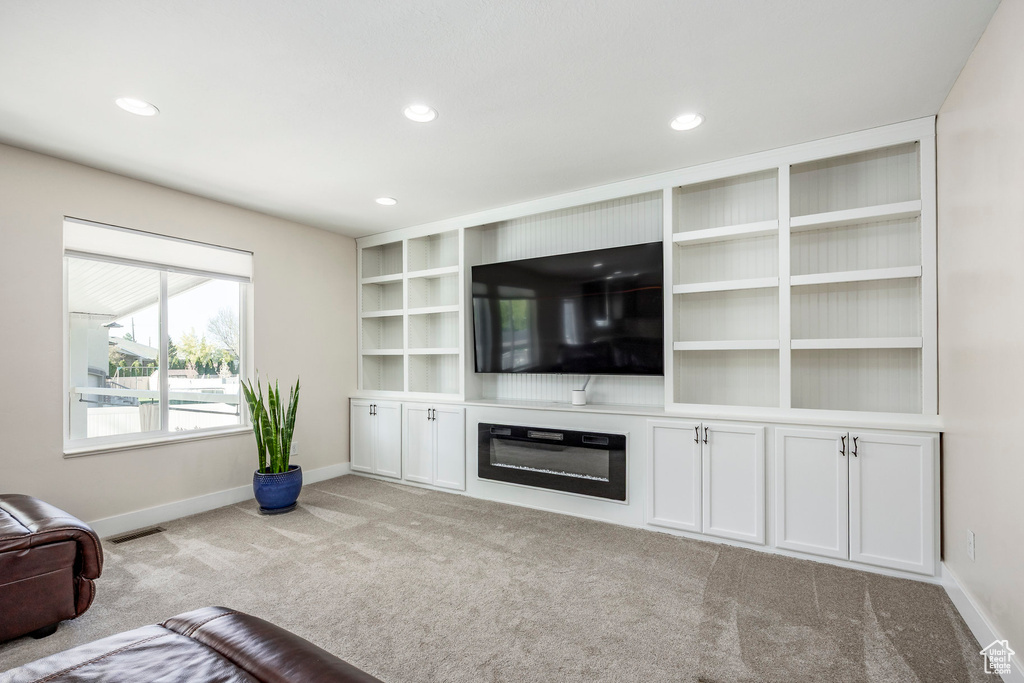 Unfurnished living room featuring carpet floors, baseboards, recessed lighting, and visible vents