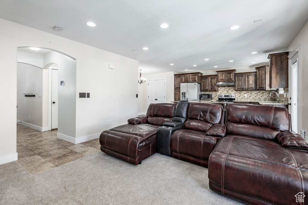 Living area with arched walkways, baseboards, recessed lighting, and light colored carpet