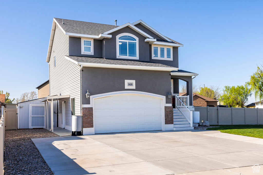 Traditional-style house with a gate, a garage, fence, concrete driveway, and stucco siding