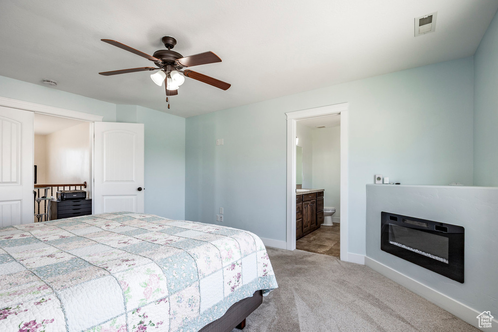 Bedroom featuring ceiling fan, light colored carpet, ensuite bath, baseboards, and visible vents