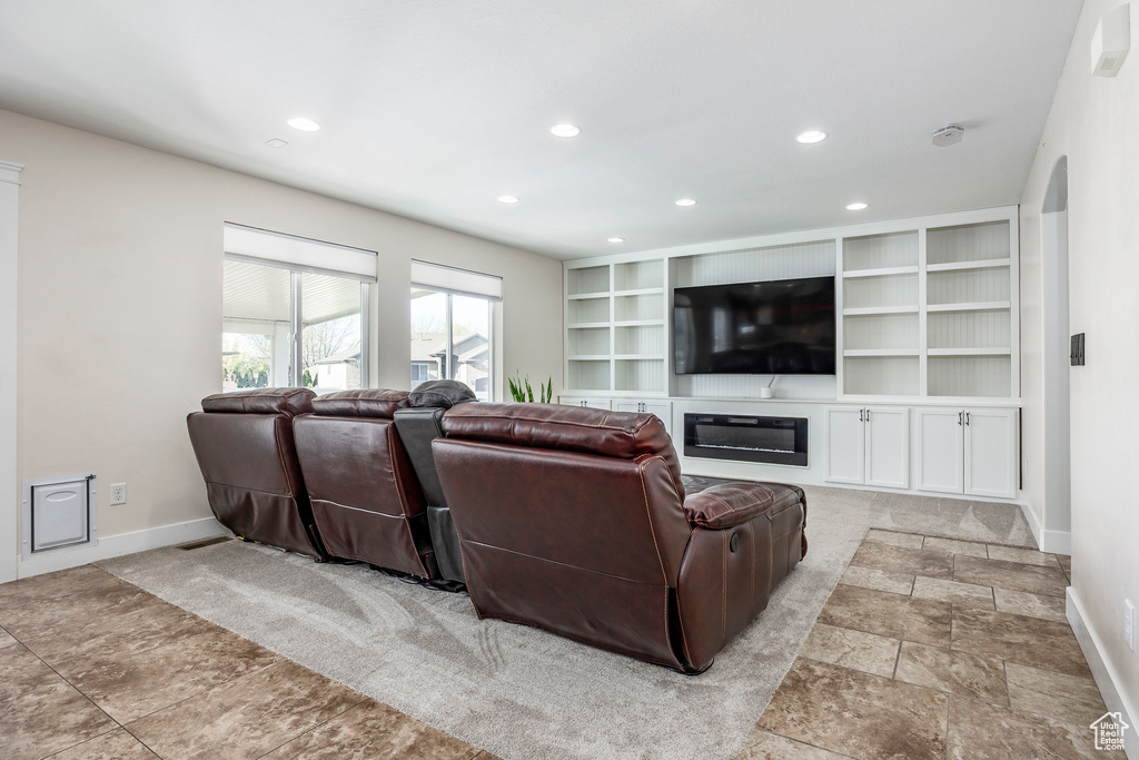Living area featuring recessed lighting, baseboards, a glass covered fireplace, and stone finish floor