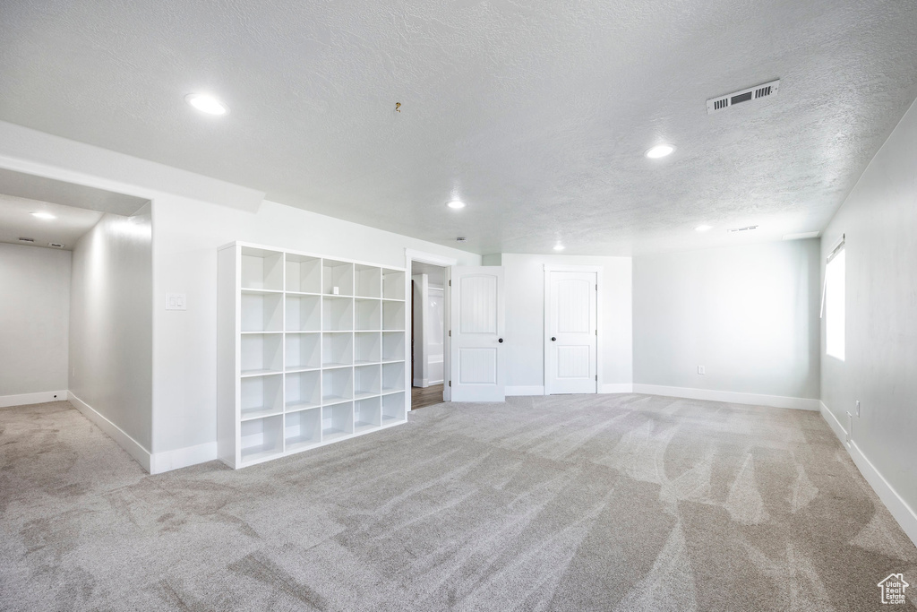 Empty room featuring baseboards, carpet flooring, a textured ceiling, and visible vents