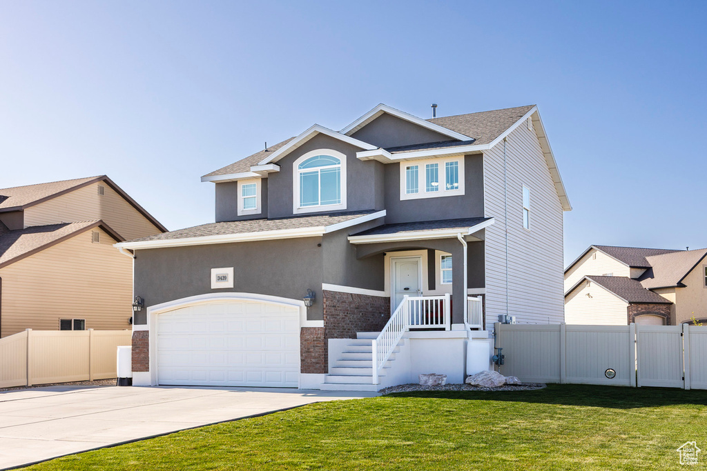 View of front of house with fence, an attached garage, stucco siding, a front yard, and concrete driveway