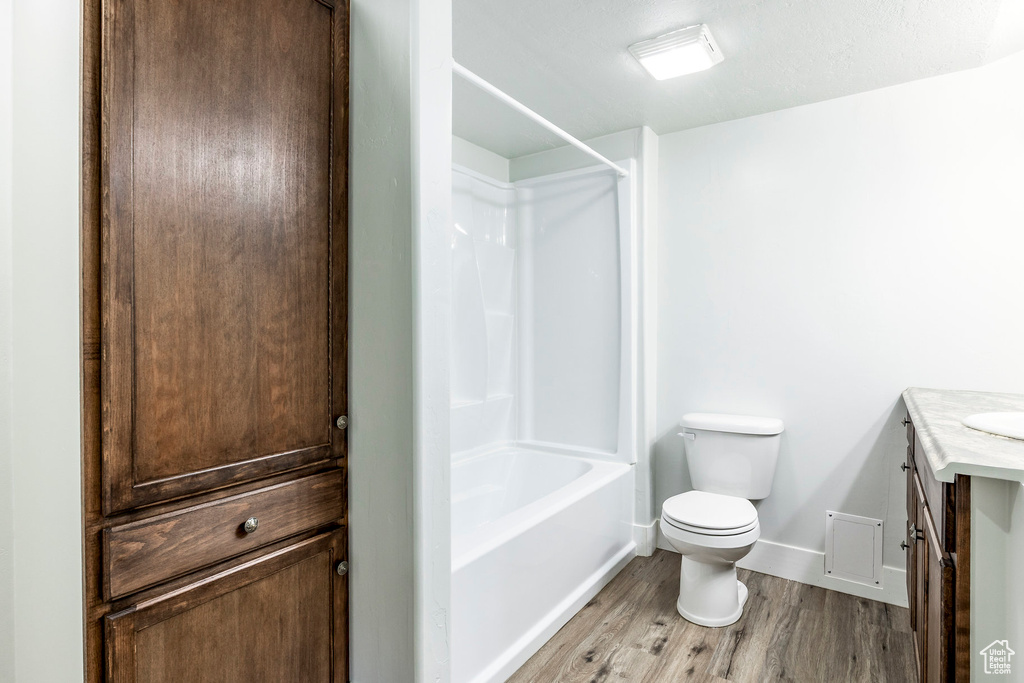 Bathroom with vanity, toilet, baseboards, bathing tub / shower combination, and wood finished floors