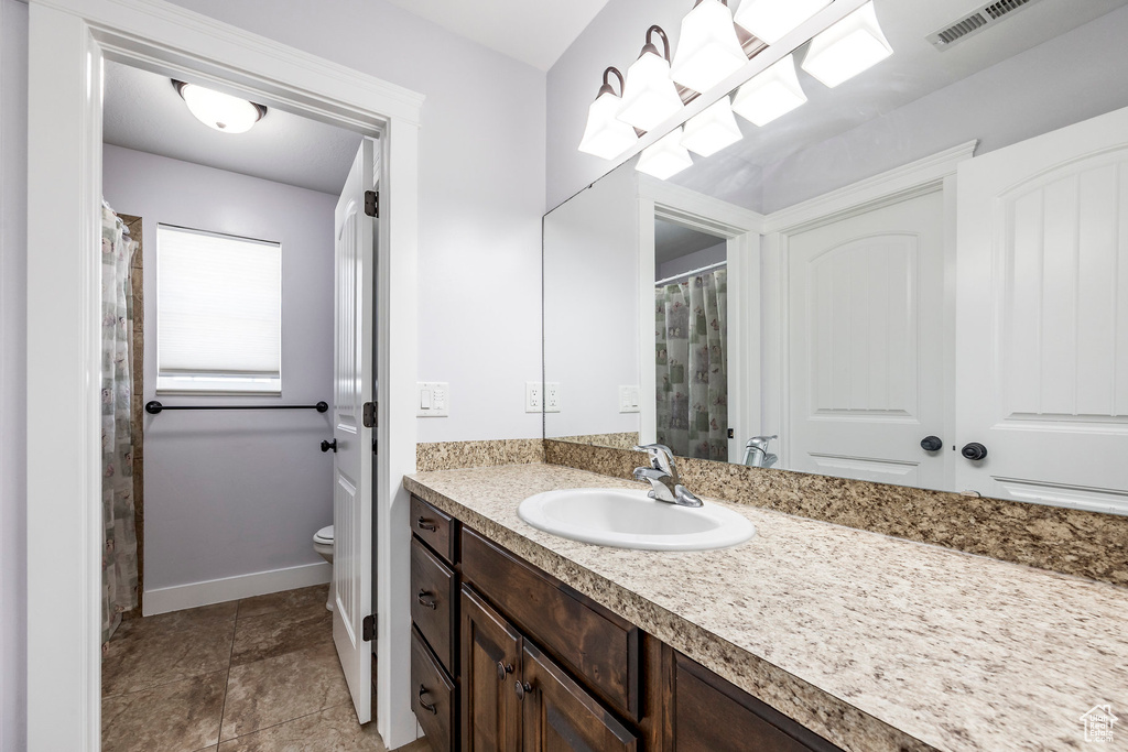 Bathroom with visible vents, vanity, toilet, baseboards, and a shower with curtain