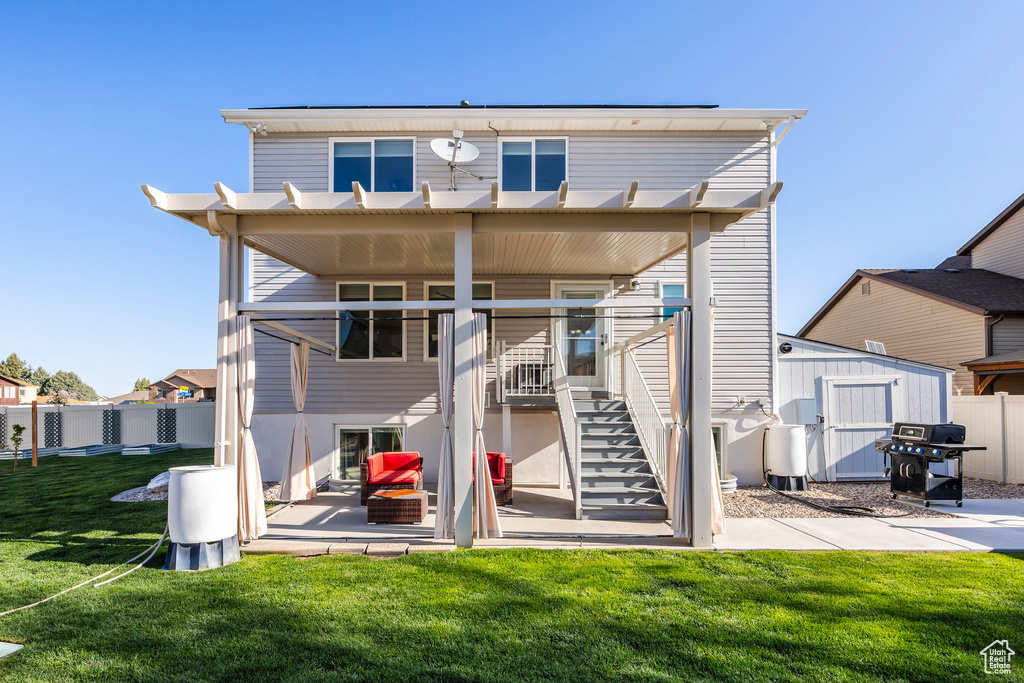 Back of property with an outdoor structure, fence, a shed, a patio area, and a yard