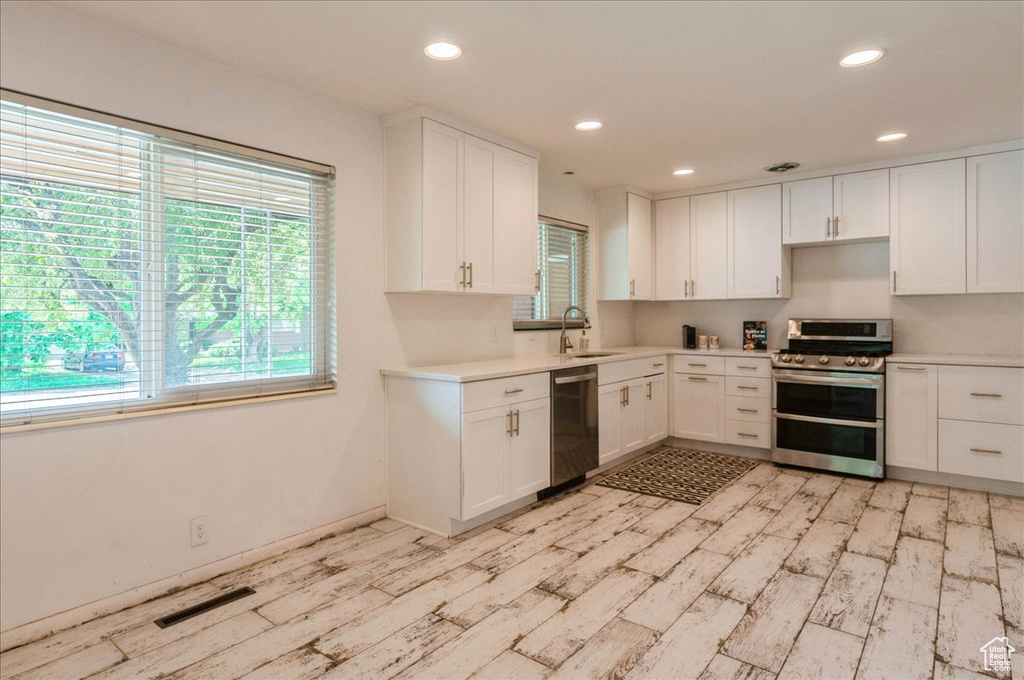 Kitchen featuring visible vents, light wood-style floors, light countertops, a sink, and appliances with stainless steel finishes