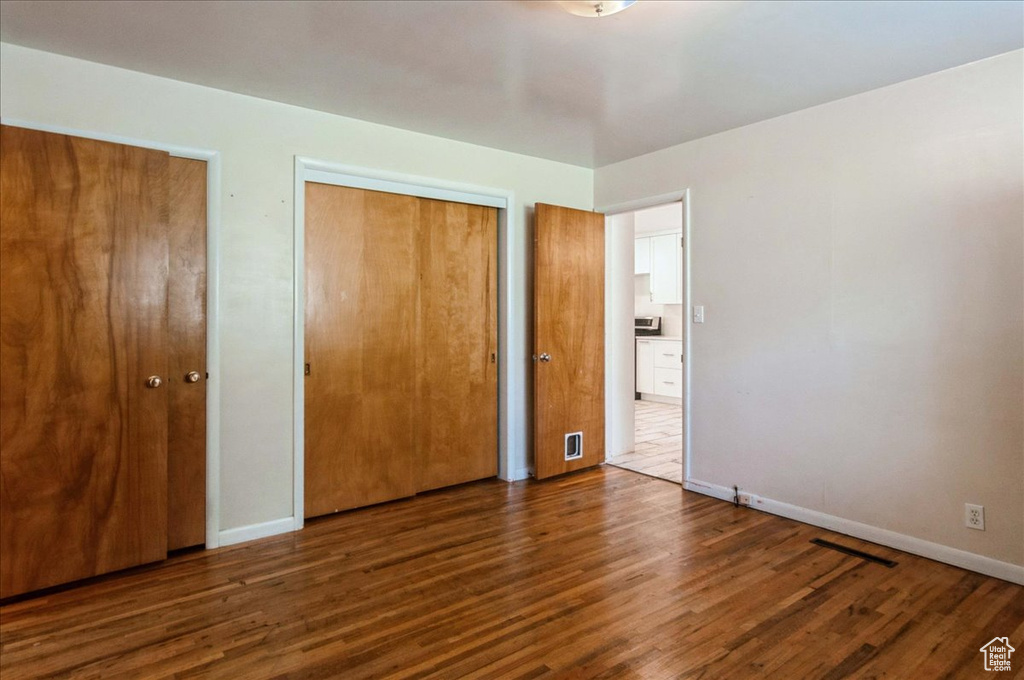Unfurnished bedroom with baseboards, wood finished floors, and visible vents