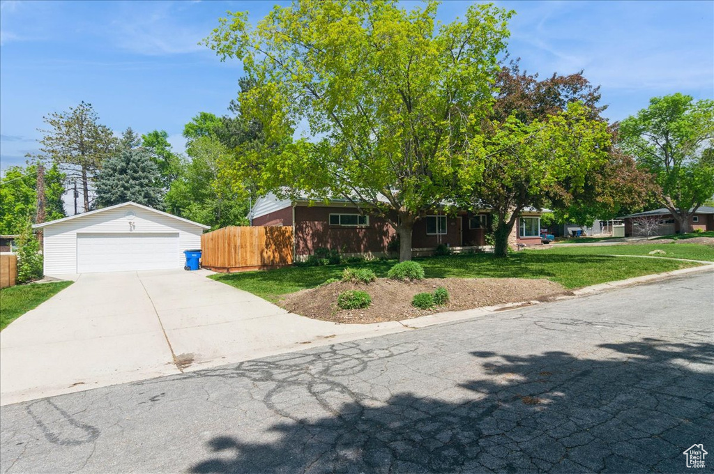 Ranch-style house with a detached garage, fence, and a front yard