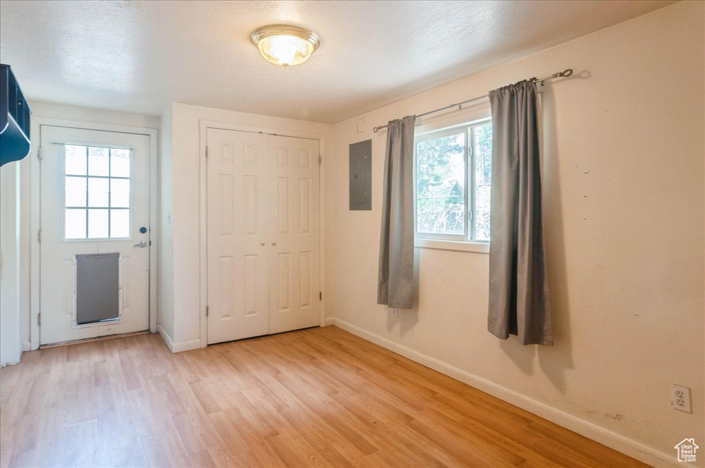 Unfurnished bedroom featuring multiple windows, electric panel, and light wood-style floors