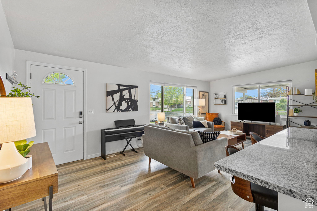 Living room with a textured ceiling, baseboards, and light wood-style floors