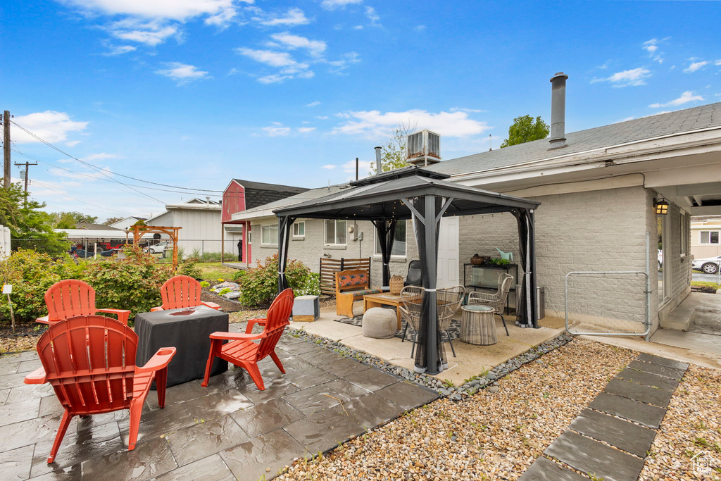 View of patio with a gazebo, fence, a fire pit, and cooling unit