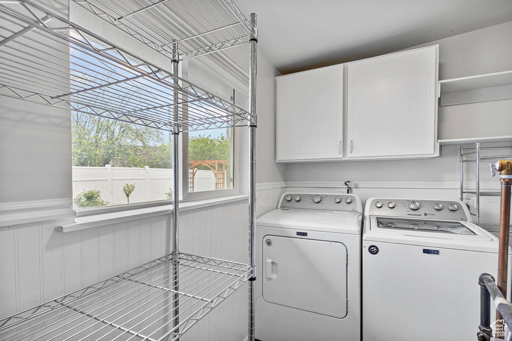 Laundry room featuring cabinet space, washing machine and dryer, and a wainscoted wall