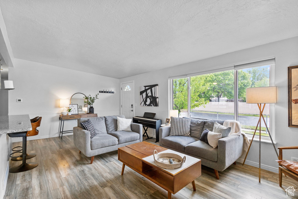 Living area featuring a textured ceiling, wainscoting, and wood finished floors