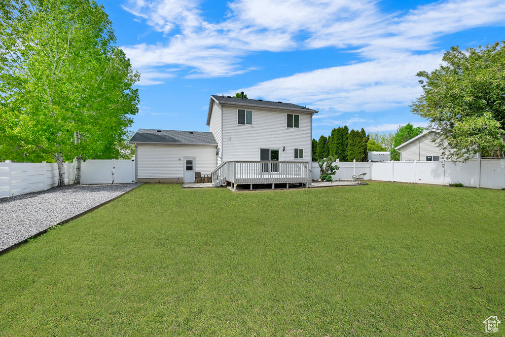 Rear view of house featuring a lawn, a wooden deck, and a fenced backyard
