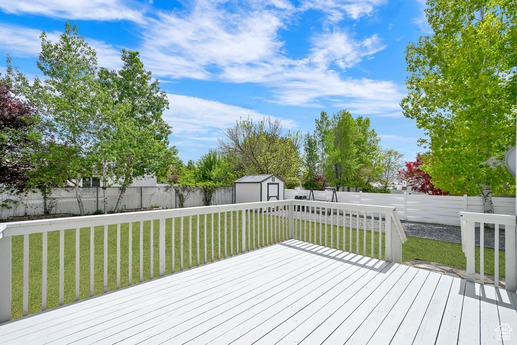 Wooden deck featuring a storage shed, a lawn, an outbuilding, and a fenced backyard