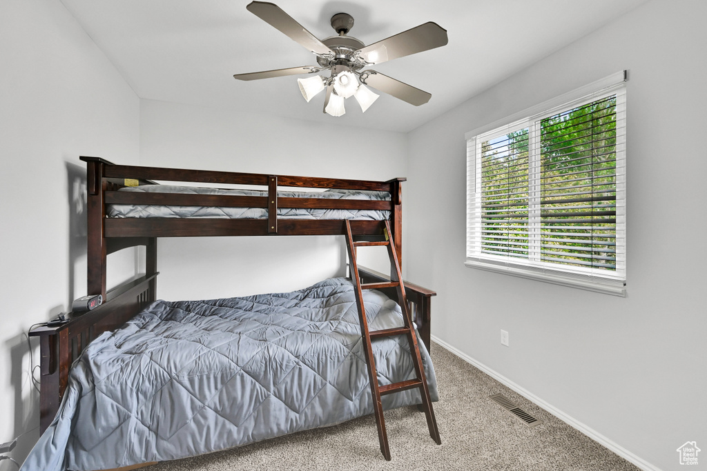 Carpeted bedroom featuring visible vents, baseboards, and ceiling fan