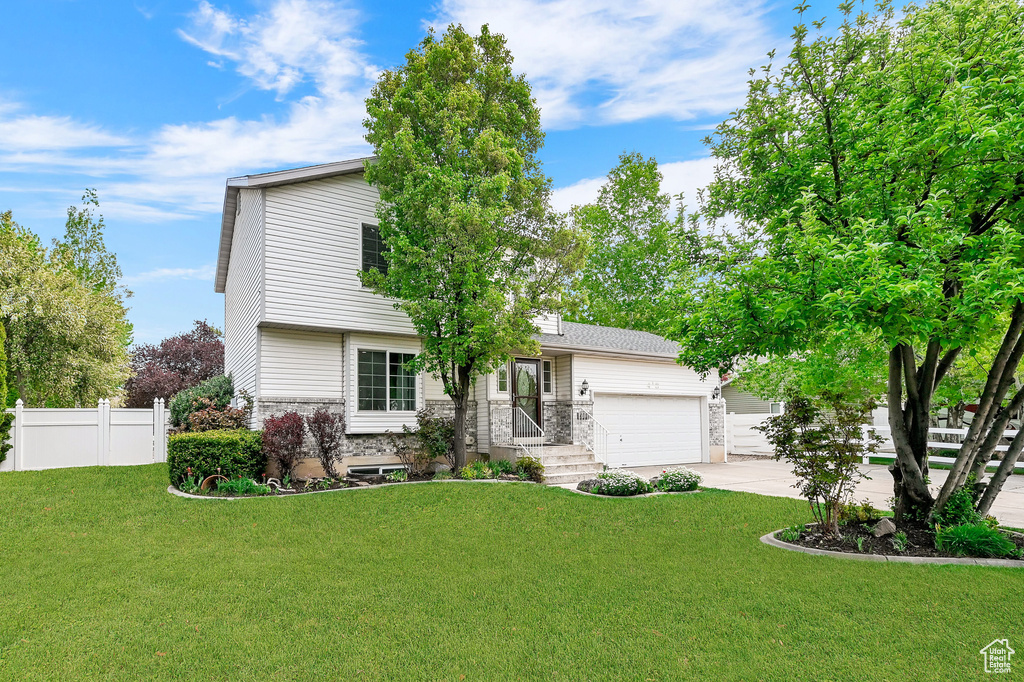 View of front of home featuring fence, an attached garage, concrete driveway, and a front lawn