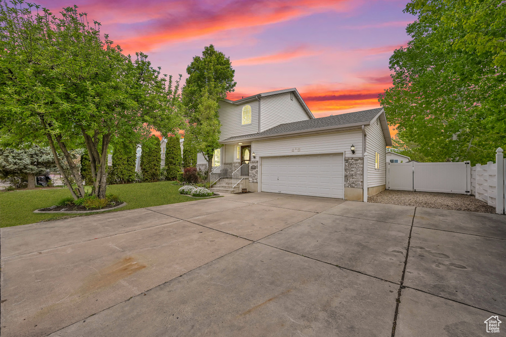 Traditional home with fence, an attached garage, a gate, concrete driveway, and a yard
