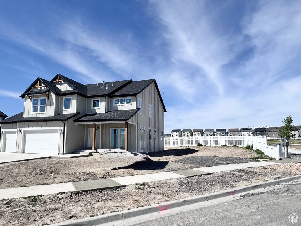 View of front of home with a garage, board and batten siding, fence, and concrete driveway