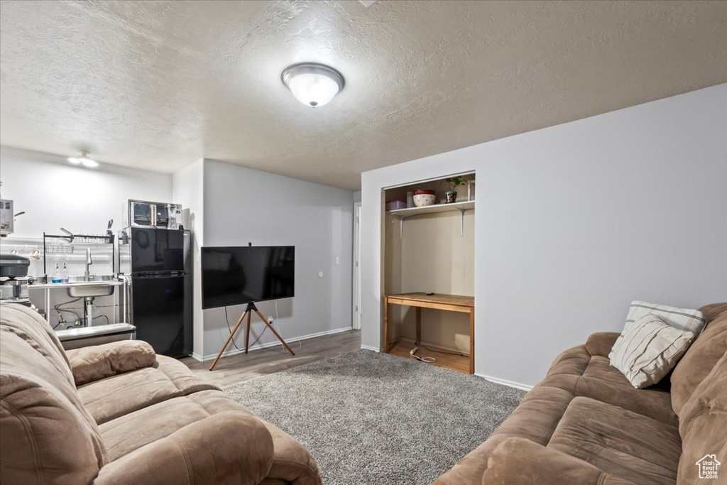 Living area with a textured ceiling, baseboards, and wood finished floors