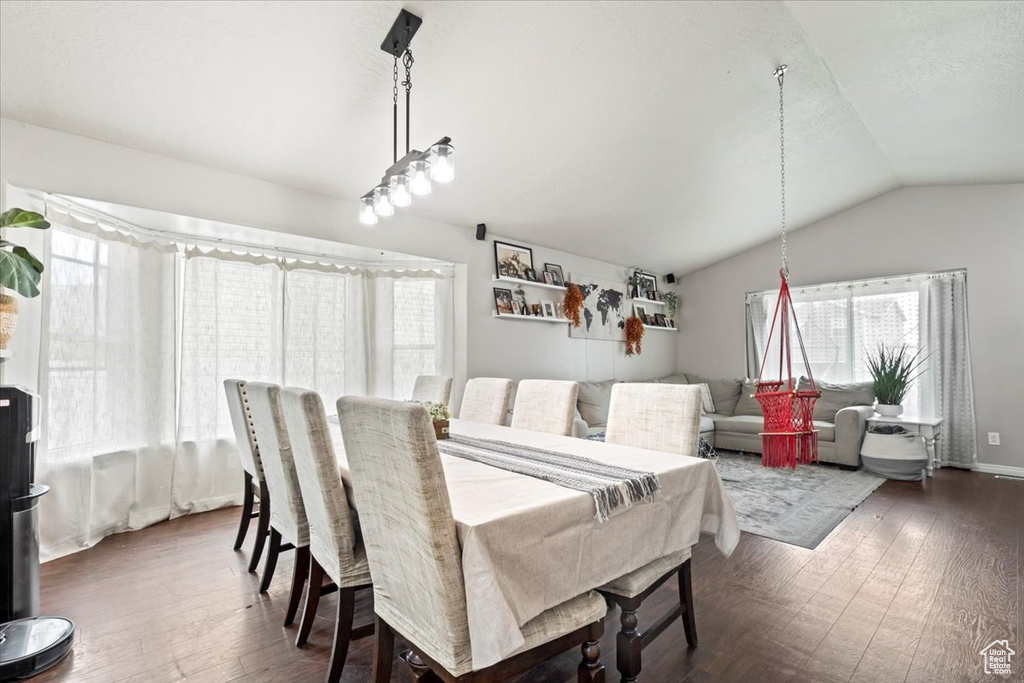 Dining room with dark wood finished floors, lofted ceiling, and a healthy amount of sunlight