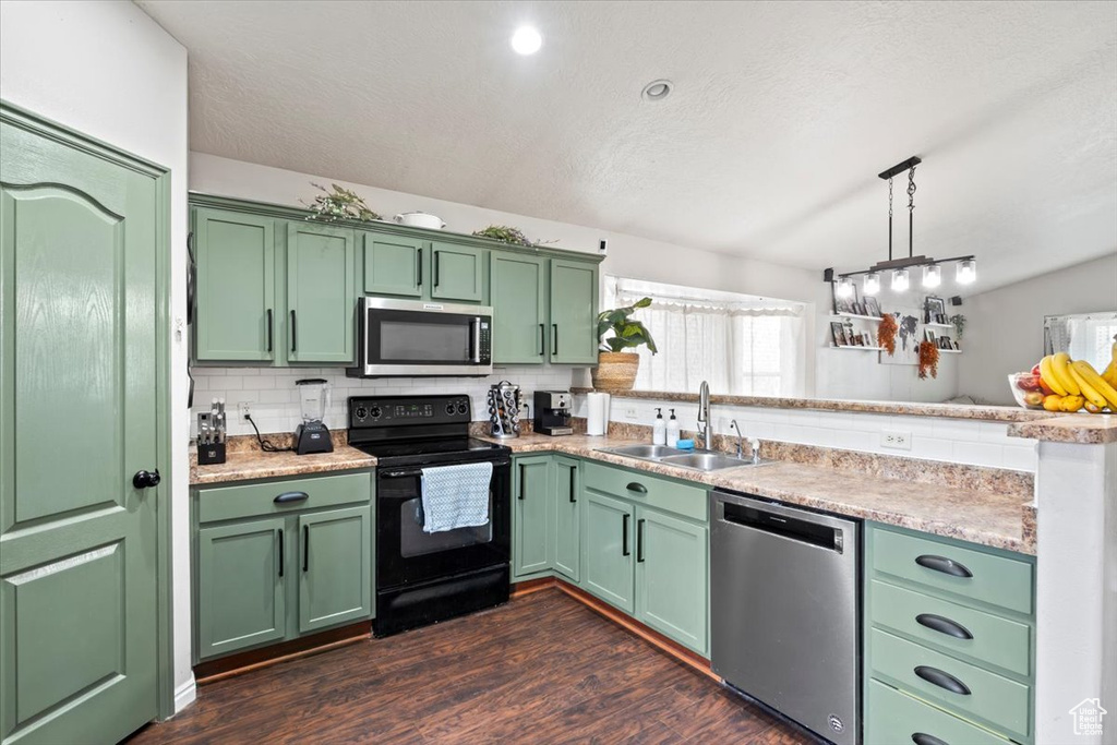 Kitchen featuring stainless steel appliances, a peninsula, a sink, and green cabinets