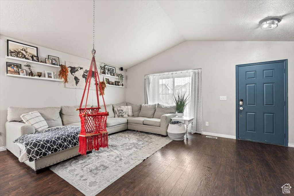 Living room featuring baseboards, vaulted ceiling, dark wood finished floors, and visible vents
